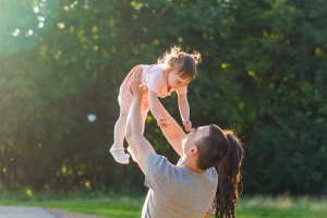 Man holding daughter in the air smiling