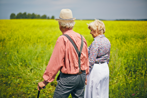 Elderly couple holding hands in a cornfield