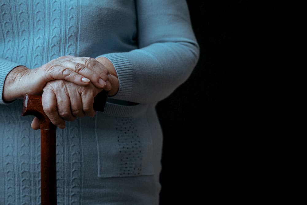 Elderly lady's hands on walking stick